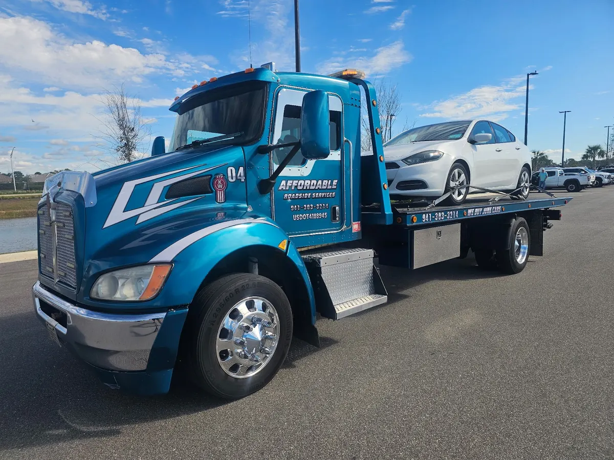 Affordable Roadside blue Kenworth rollback with a white car loaded on the bed